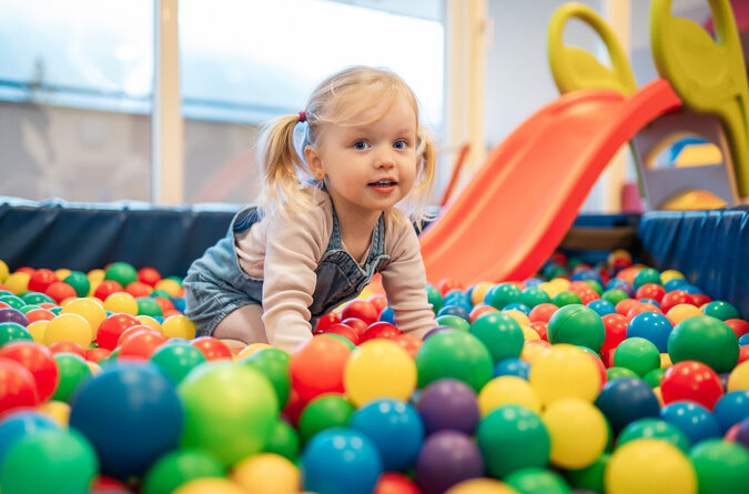 Mädchen spielt im bunten Bällebad des Kinderhotels Ein Mädchen spielt im bunten Bällebad eines Kinderhotels.